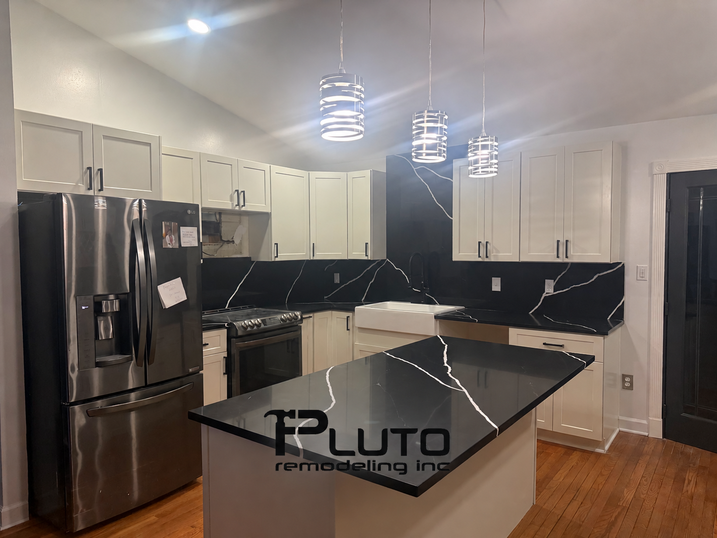 White cabinetry, black countertops and a kitchen island — Pluto Remodeling